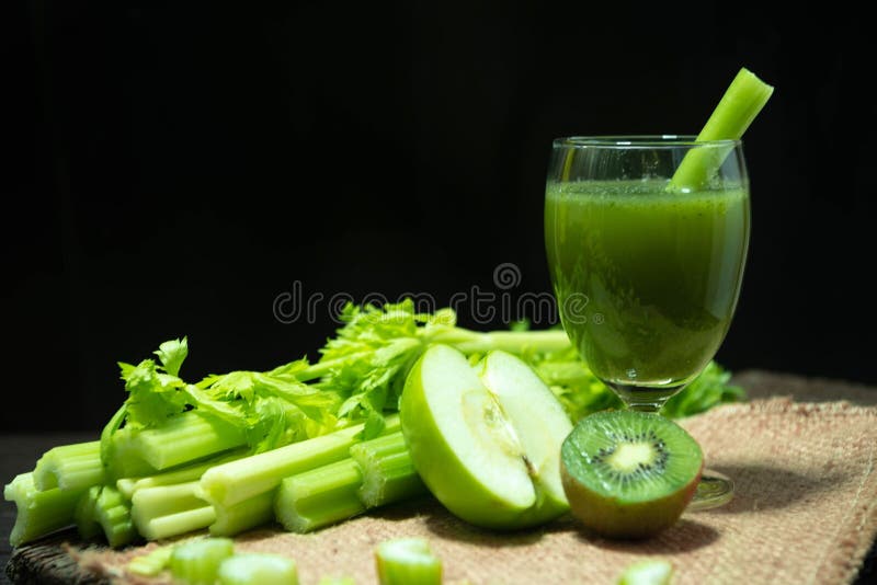 Blended mezcló el apio del jugo y kiwi y manzana verde en vidrio de la bebida agradable y manojo de tallo fresco del apio en la t fotografía de archivo