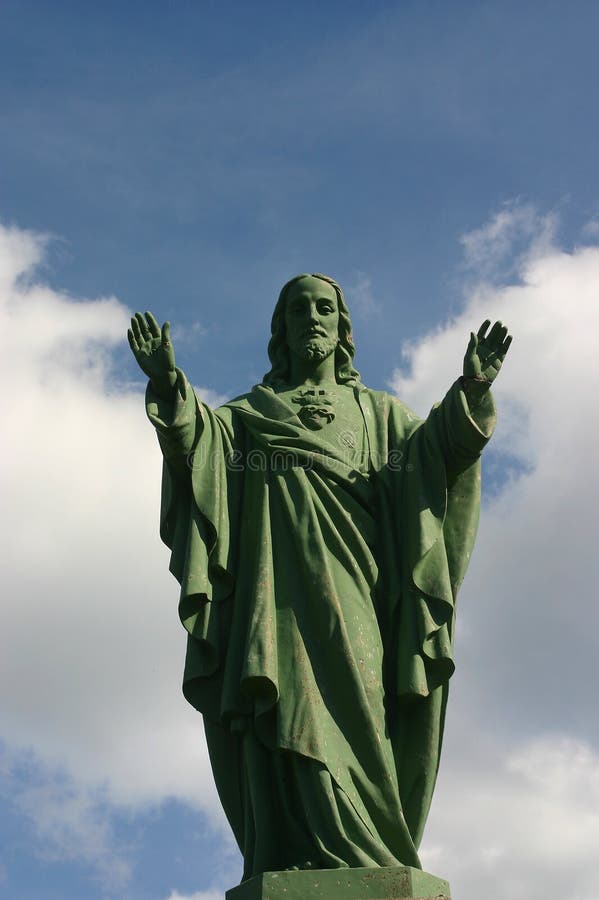 A statue of jesus blessing, against a blue sky with some small white clouds. A statue of jesus blessing, against a blue sky with some small white clouds