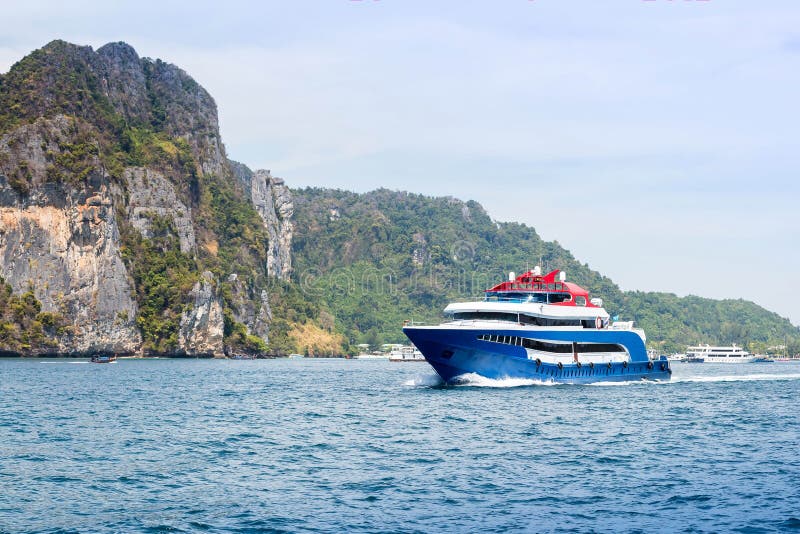 Bleu avec le bateau blanc et rouge de vitesse de plaisir d'accents Navigation sur la mer contre une île tropicale Front View images stock Bleu avec le bateau blanc et rouge de vitesse de plaisir d'accents Navigation sur la mer contre une île tropicale Front View images stock