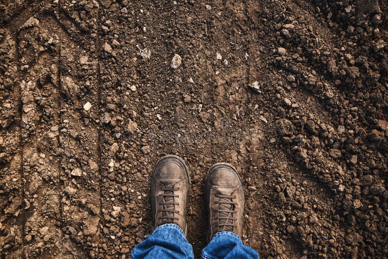 Top view of farmer's feet in boots standing on countryside dirt road, copy space included. Top view of farmer's feet in boots standing on countryside dirt road, copy space included