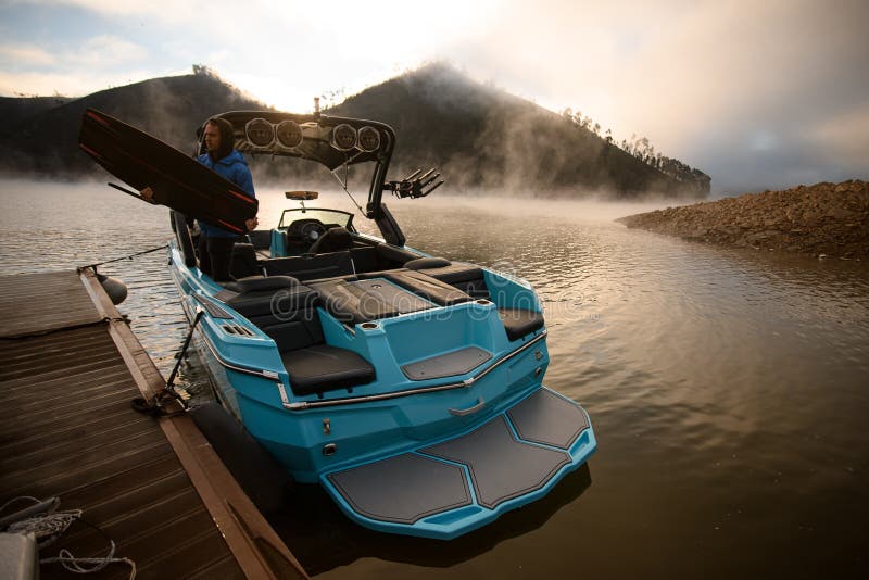 Blick auf das Boot, das am Pier festgemacht ist, und einen Mann mit einem Wakeboard in den Händen lizenzfreies stockfoto