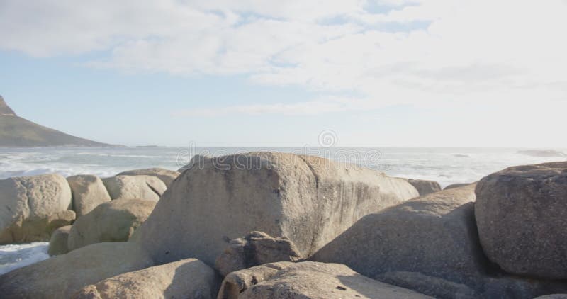 Blick auf die Wellen, die am Strand auf Felsen stürzen und dadurch eine ruhige Küstenlandschaft schaffen stock video footage