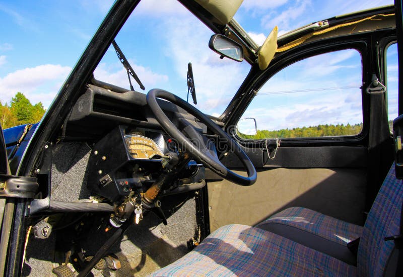 Blick in das klassische französische Kultfahrzeug 2CV auf Vordersitz, Armaturenbrett und Lenkrad mit offenem Klappdach und Fenste stockfotos