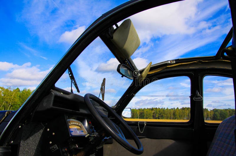 Blick in das klassische französische Kultfahrzeug 2CV auf Vordersitz, Armaturenbrett und Lenkrad mit offenem Klappdach und Fenste lizenzfreie stockfotografie