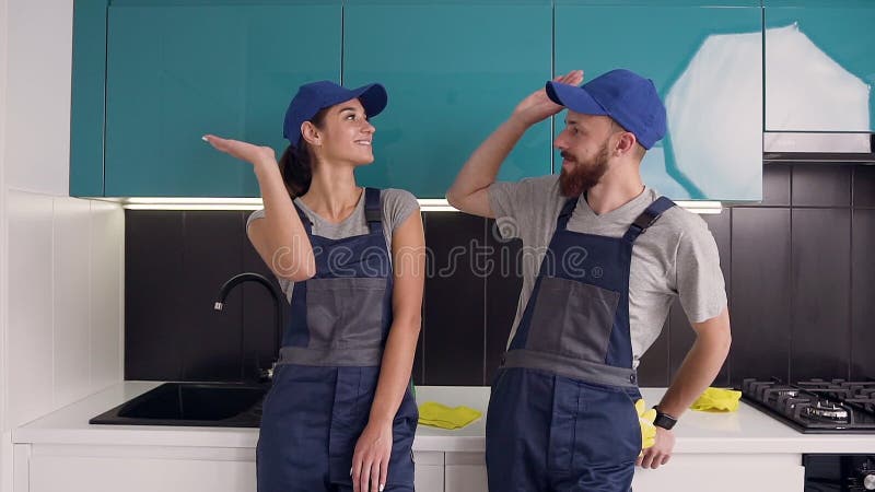 Blij dat ze tevreden waren over hun werk, man en vrouw van de schoonmaakdienst die hoge vijf in de blauwe zwarte keuken gaf