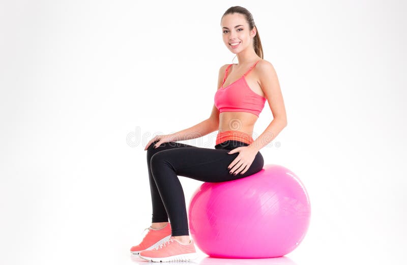 Blije aantrekkelijke jonge sportvrouwzitting op roze fitball stock foto Blije aantrekkelijke jonge sportvrouwzitting op roze fitball stock foto