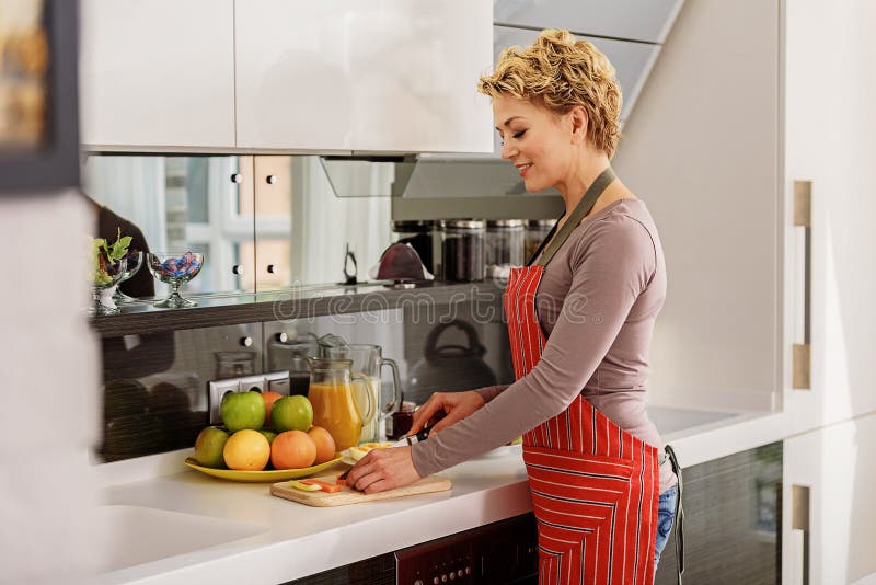 Blije huisvrouw die gezond voedsel voorbereiden stock afbeeldingen Blije huisvrouw die gezond voedsel voorbereiden stock afbeeldingen