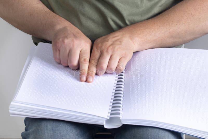 Blind man was reading a book written on Braille. Horizontal