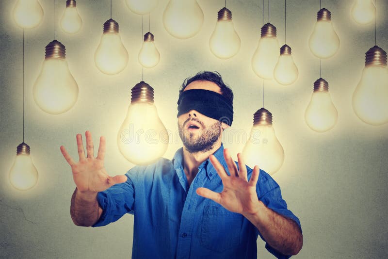 Blindfolded man walking through light bulbs searching for bright idea