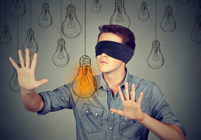 Blindfolded man walking through light bulbs searching for idea