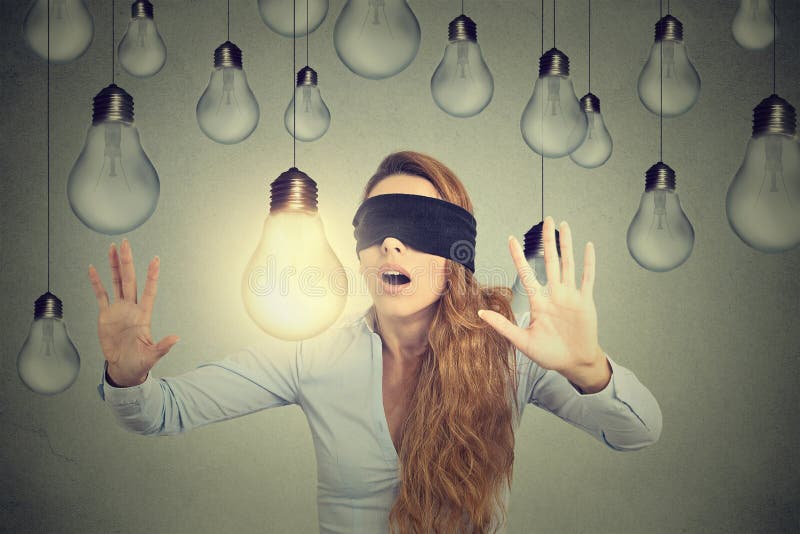 Blindfolded woman walking through lightbulbs searching for bright idea