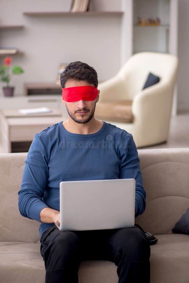 Blindfolded young male freelancer working from home