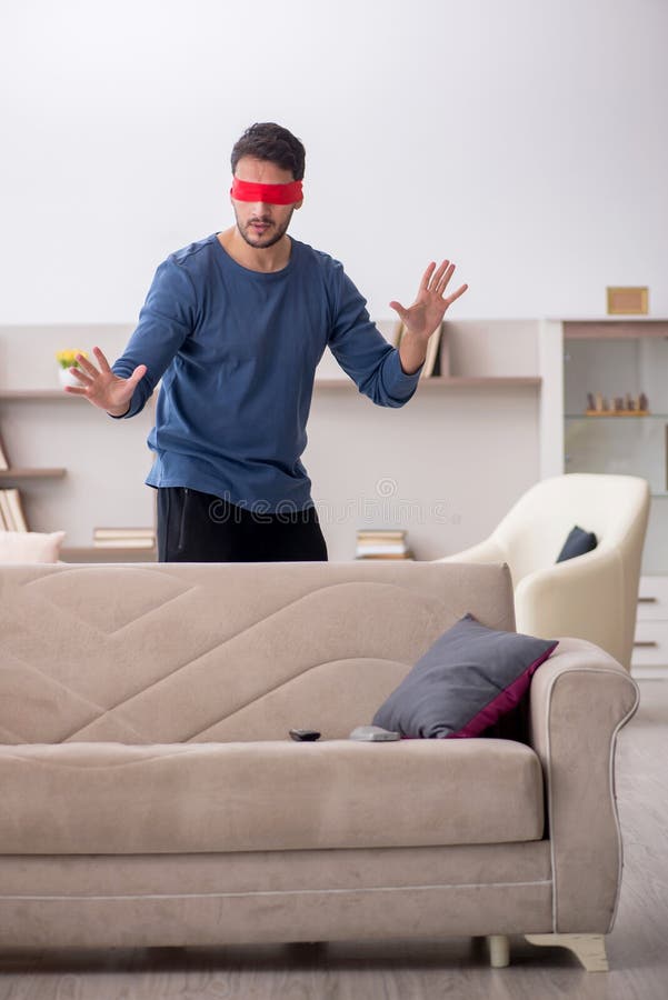 Blindfolded young man at home