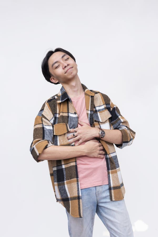 A blissful young asian man rubbing his stomach feeling satiated and full. Isolated on a white background stock photos