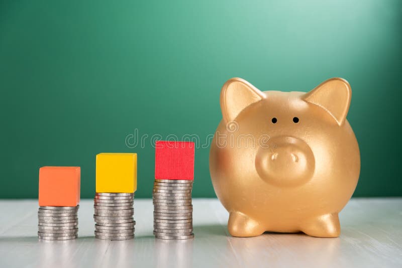 Bloc en bois de cube sur la pile croissante de pièces de monnaie et la tirelire image stock Bloc en bois de cube sur la pile croissante de pièces de monnaie et la tirelire image stock