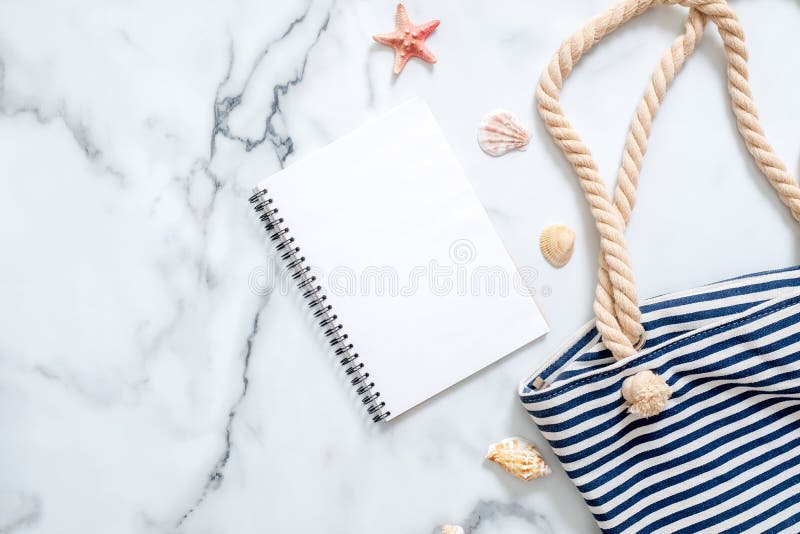 Blocco note in bianco, borsa a strisce di estate, conchiglie su fondo di marmo Lo scrittorio delle donne del viaggiatore, blogger fotografia stock libera da diritti Blocco note in bianco, borsa a strisce di estate, conchiglie su fondo di marmo Lo scrittorio delle donne del viaggiatore, blogger fotografia stock libera da diritti