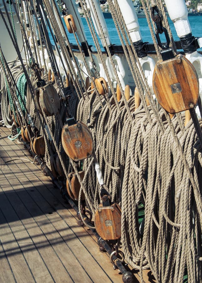 Wooden blocks with ropes on the mast - tackles on the board of the ship. Rigging, marine ropes and pulleys on the old ship. Ancient sailing vessel - marine background with wooden rigging and ropes.