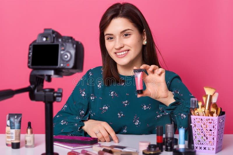 Blogger famoso Productos femeninos alegres de los cosméticos que muestran mientras que registra el vídeo y del donante los consej fotografía de archivo libre de regalías Blogger famoso Productos femeninos alegres de los cosméticos que muestran mientras que registra el vídeo y del donante los consej fotografía de archivo libre de regalías