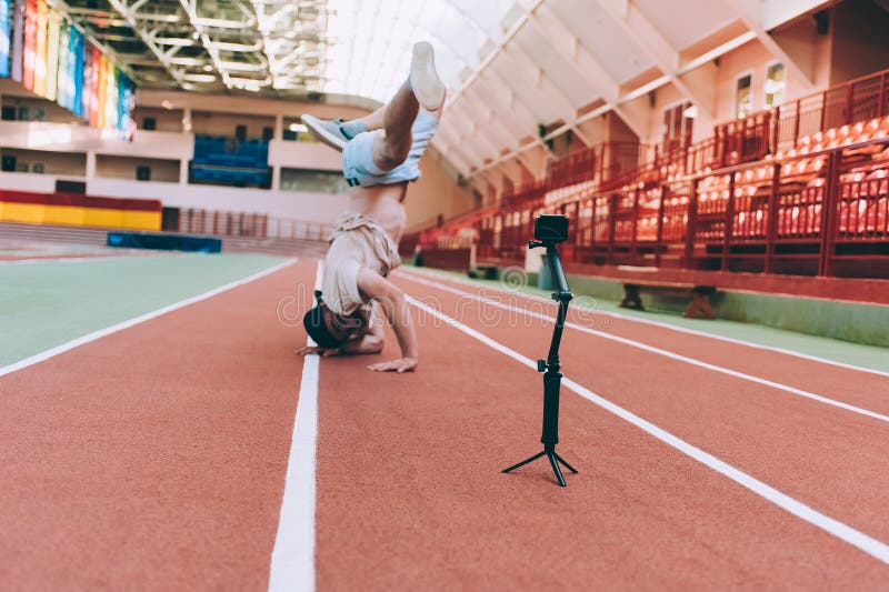 Blogger in the Stadium Shoots Video with Action Camera. Break Dance