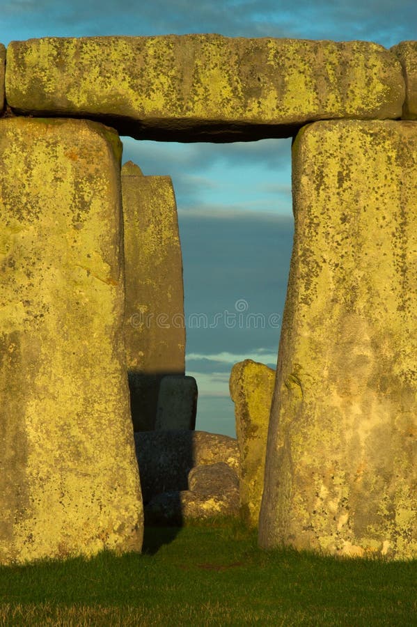 A single section of Stonehenge blocks in the evening sun with pale blue clouds and grass. A single section of Stonehenge blocks in the evening sun with pale blue clouds and grass.