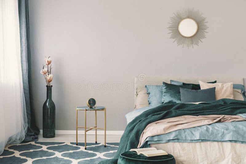 Blommor i stilfull flaska som vasen bredvid moderiktig nightstand med klockan i det härliga sovrummet som är inre med beiga och s royaltyfria bilder Blommor i stilfull flaska som vasen bredvid moderiktig nightstand med klockan i det härliga sovrummet som är inre med beiga och s royaltyfria bilder