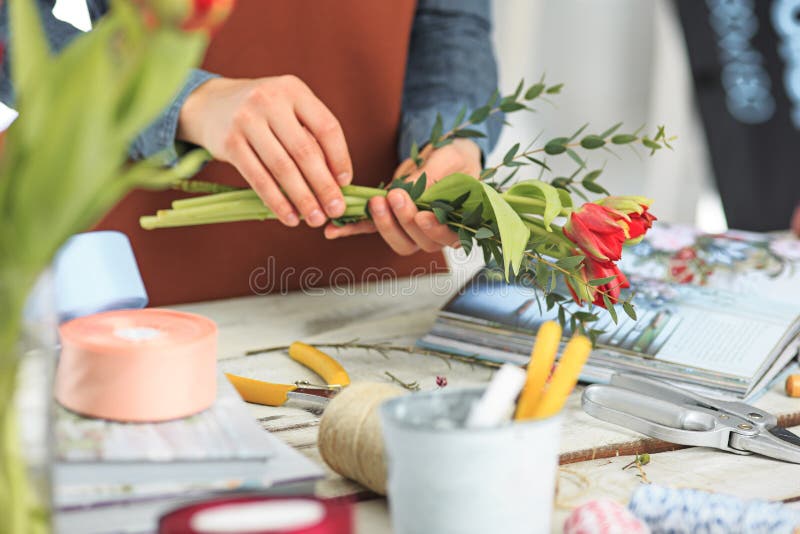 Blomsterhandlare på arbete: de kvinnliga händerna av kvinnadanande danar den moderna buketten av olika blommor royaltyfri fotografi Blomsterhandlare på arbete: de kvinnliga händerna av kvinnadanande danar den moderna buketten av olika blommor royaltyfri fotografi