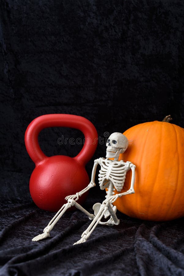 Blomsterhet, orange pumpa, rödkettlebell och vitt skelett på svart sammetsbakgrund fotografering för bildbyråer