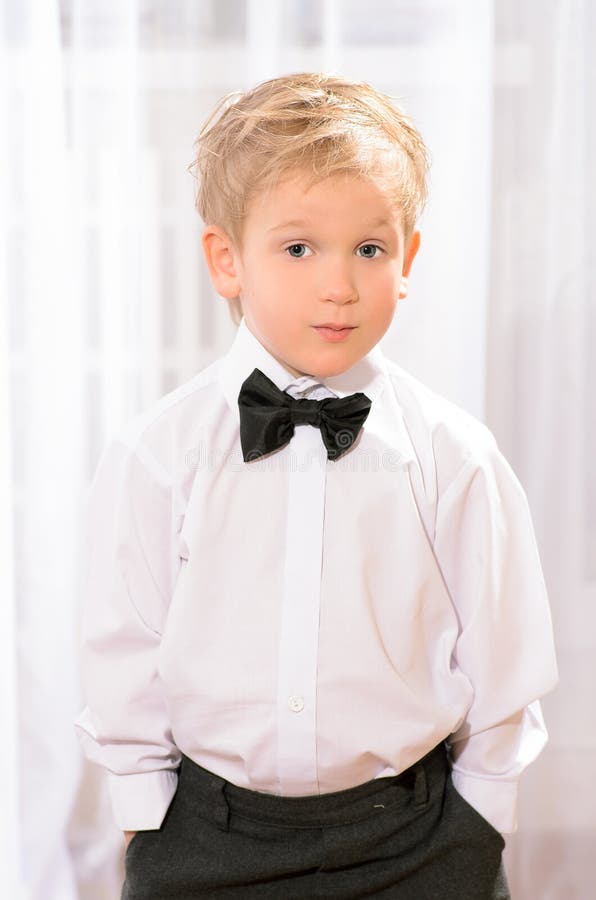 Blond boy in white shirt with black bow tie royalty free stock photo Blond boy in white shirt with black bow tie royalty free stock photo