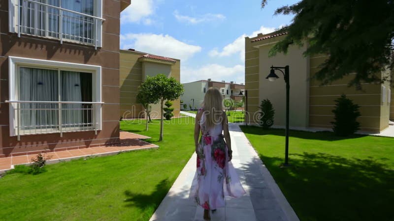 Blond dam som går nära hus lager videofilmer
