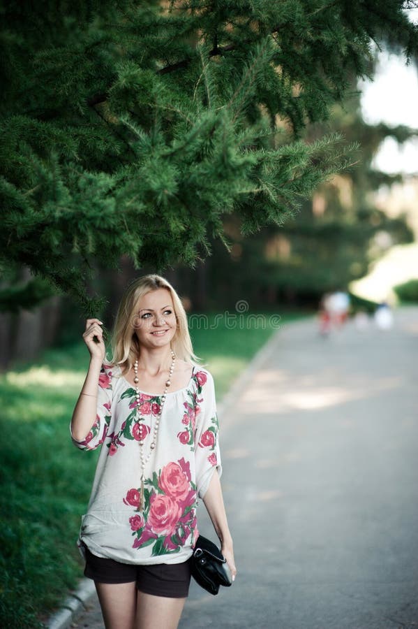 Blond flicka i broderi nära ettträd på en gå royaltyfri bild Blond flicka i broderi nära ettträd på en gå royaltyfri bild