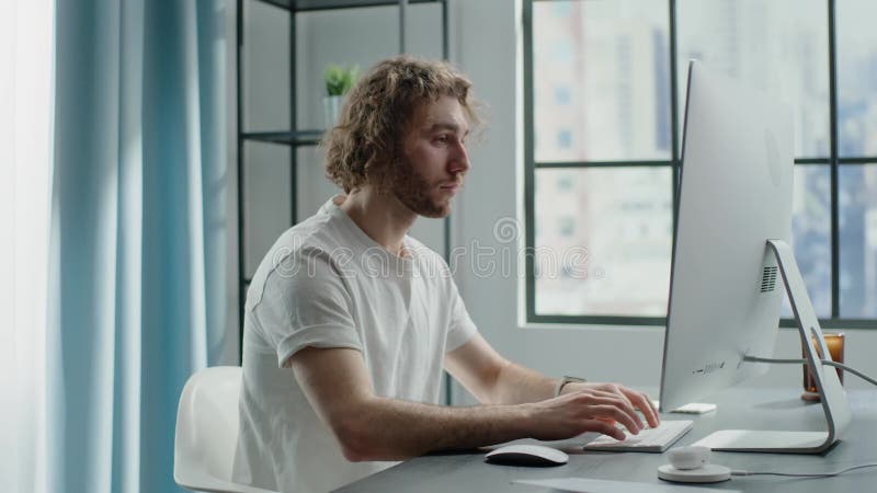 Blond freelancer works on computer and chats on smartphone