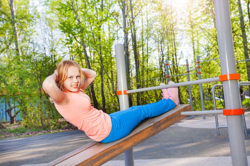 Blond girl curls up on board at the sports ground.
