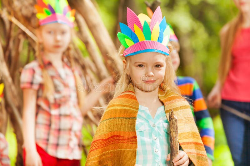 Blond girl in Injun`s costume playing with friends