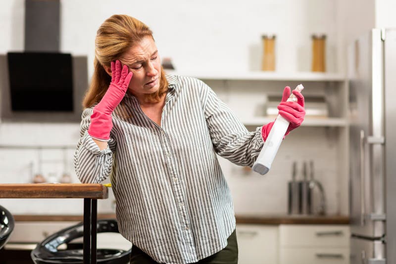 Cleaning chemicals. Blond-haired woman in striped shirt having strong allergy to cleaning chemicals. Cleaning chemicals. Blond-haired woman in striped shirt having strong allergy to cleaning chemicals