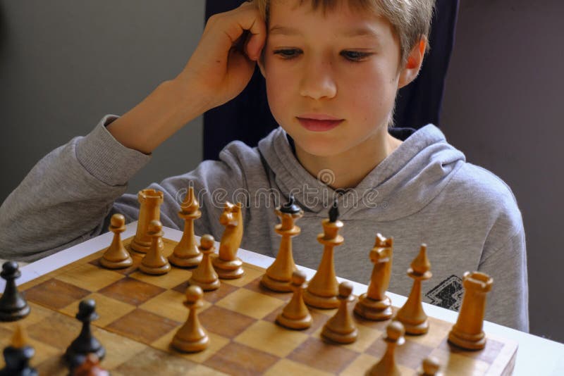 Blond kaukaski chłopiec myślący o następnym ruchu szachowym grającym w szachy. koncepcja planowania strategii