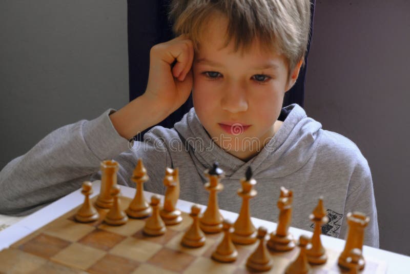 Blond kaukaski chłopiec myślący o następnym ruchu szachowym grającym w szachy. koncepcja planowania strategii