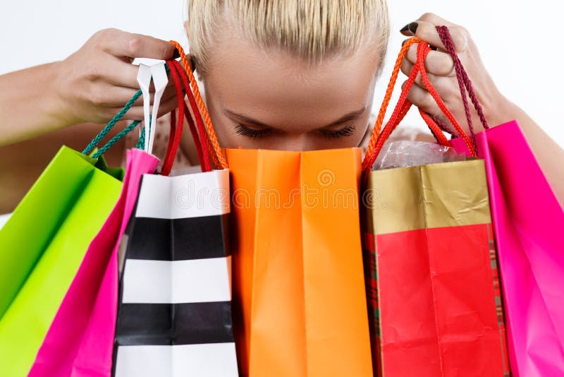 Blond kvinna som kontrollerar innehållet av kulöra pappers- påsar med nytt royaltyfria bilder Blond kvinna som kontrollerar innehållet av kulöra pappers- påsar med nytt royaltyfria bilder