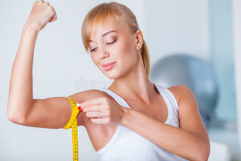 Blond kvinna som mäter biceps arkivbild Blond kvinna som mäter biceps arkivbild