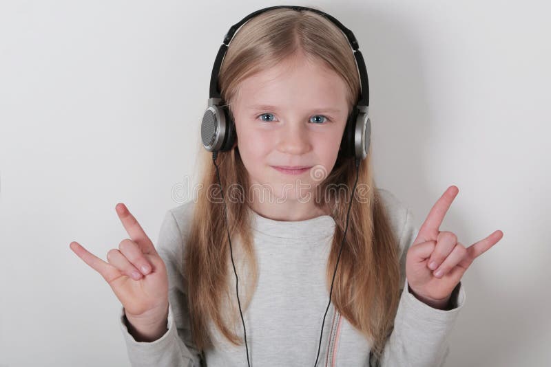 Blond meisje met hoofdtelefoons het luisteren muziek en het zingen Leuk meisje die een rots-n-broodje maken ondertekenen stock afbeeldingen Blond meisje met hoofdtelefoons het luisteren muziek en het zingen Leuk meisje die een rots-n-broodje maken ondertekenen stock afbeeldingen