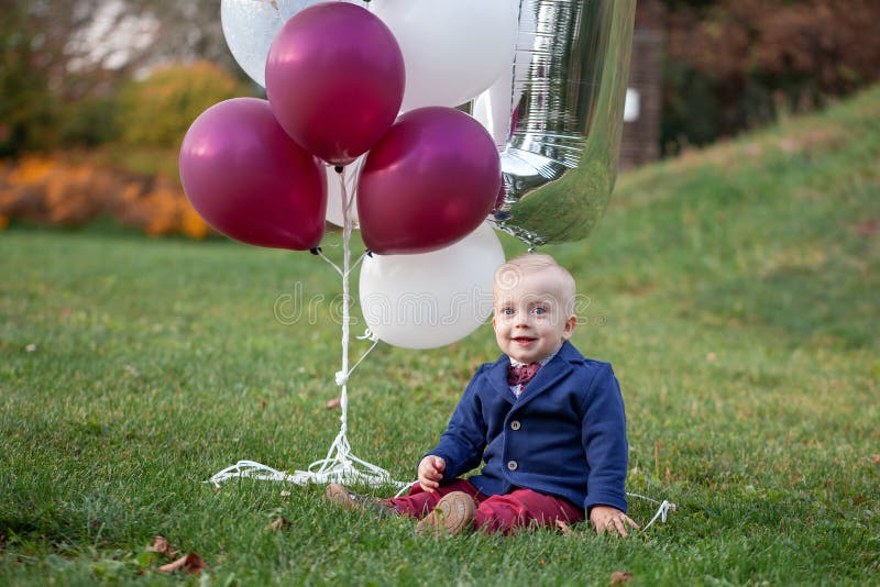 Blond souri espiègle mignon garçon de 1 années s'asseyant sur l'outdor d'herbe verte dans le jour d'été ensoleillé image libre de droits Blond souri espiègle mignon garçon de 1 années s'asseyant sur l'outdor d'herbe verte dans le jour d'été ensoleillé image libre de droits