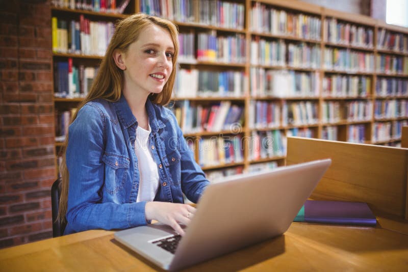 Student blonde. Студентка блондинка в библиотеке. Девушка смотрит в ноутбук Apple в библиотеке.