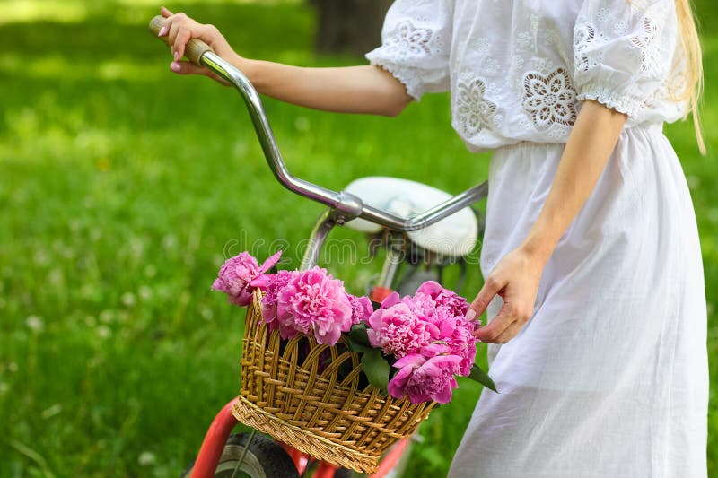 Blond woman in park with bicycle carrying a beautiful basket of