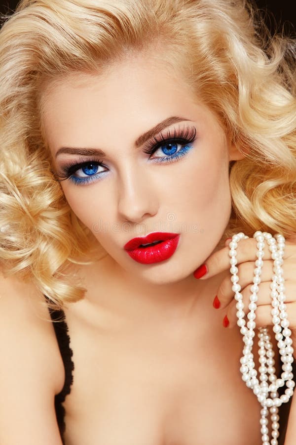 Young beautiful woman with blond curly hair holding pearls in her hand. Young beautiful woman with blond curly hair holding pearls in her hand