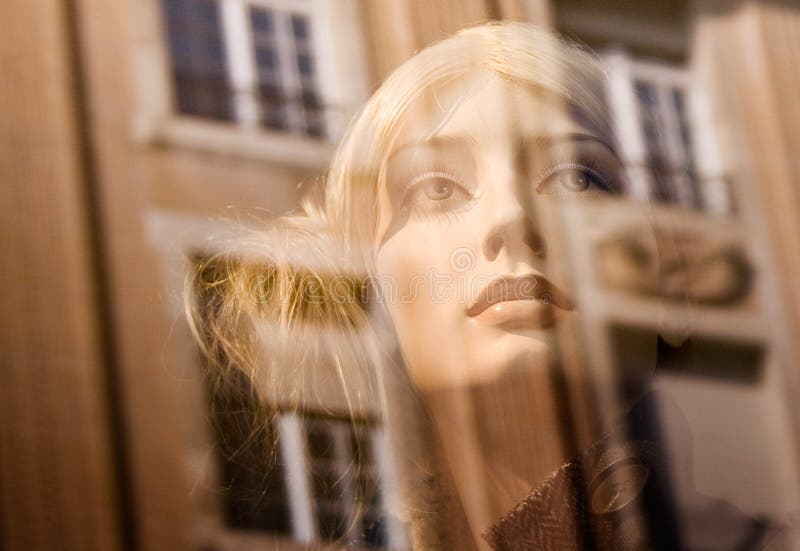 Beautiful Blonde behind a shop window. Reflections of the surrounding buildings. Beautiful Blonde behind a shop window. Reflections of the surrounding buildings.