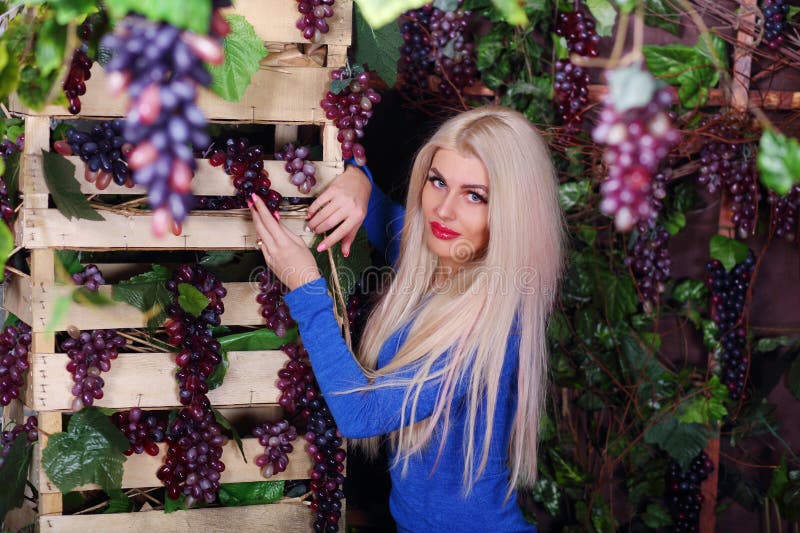 Blonde Frau in blauen Kleidern Posen unter Weinreben. Blonde Frau in blauen Kleidung Posen unter Weinreben im Studio
