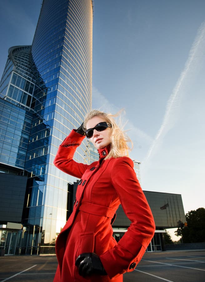 Beautiful young blond woman outdoors. Modern building behind her. Beautiful young blond woman outdoors. Modern building behind her