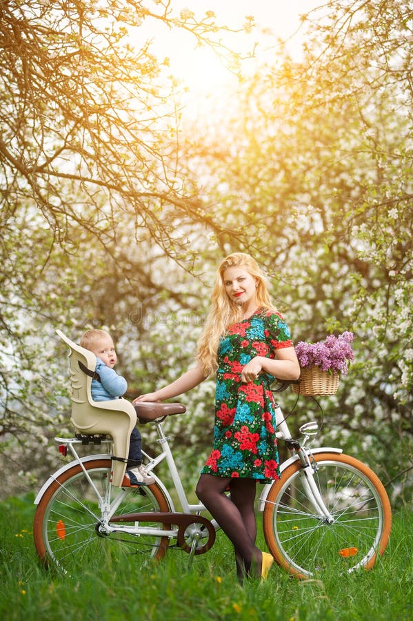 Blonde Frau mit Stadtfahrrad mit Baby im Fahrradstuhl lizenzfreies stockbild Blonde Frau mit Stadtfahrrad mit Baby im Fahrradstuhl lizenzfreies stockbild