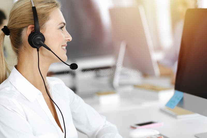 Blonde Geschäftsfrau mit Headset für Kommunikation und Beratung von Menschen im sonnigen Büro. Call Center stockfotos