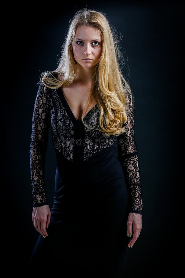 Blonde girl on a black background in a dark guipure dress