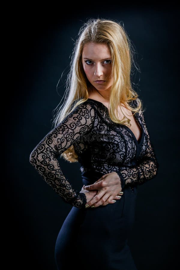 Blonde girl on a black background in a dark guipure dress